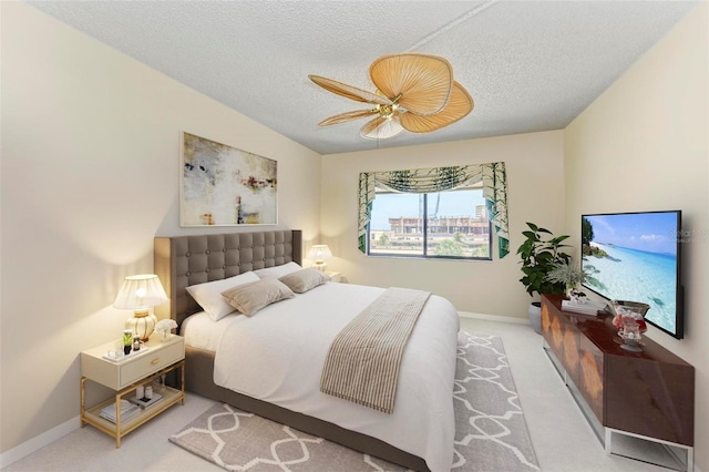 carpeted bedroom featuring ceiling fan and a textured ceiling