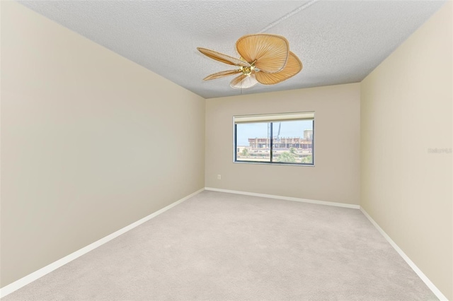 carpeted empty room featuring ceiling fan and a textured ceiling