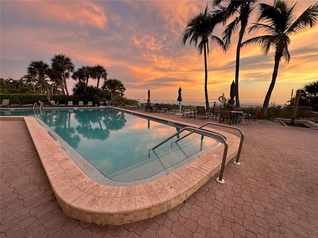 pool at dusk featuring a patio area