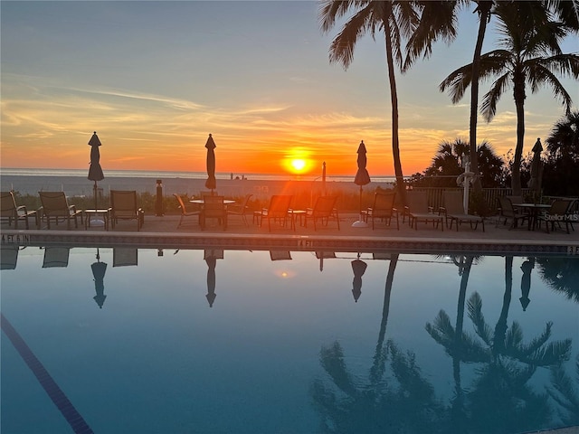 pool at dusk featuring a water view