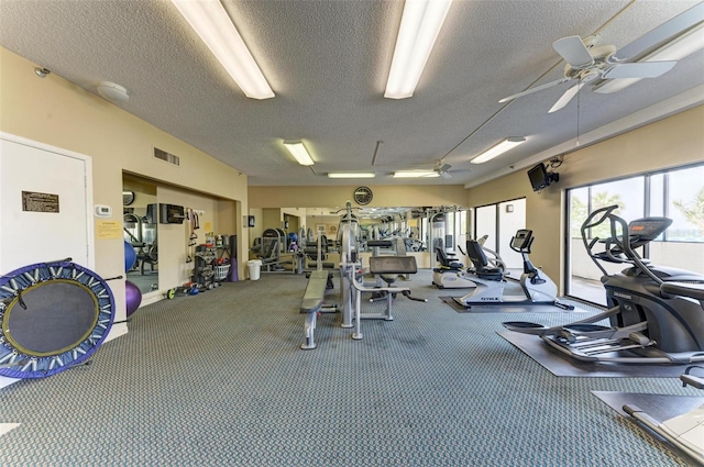 exercise room with ceiling fan, carpet, and a textured ceiling