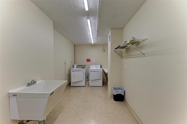 washroom featuring washer and dryer, a textured ceiling, and sink