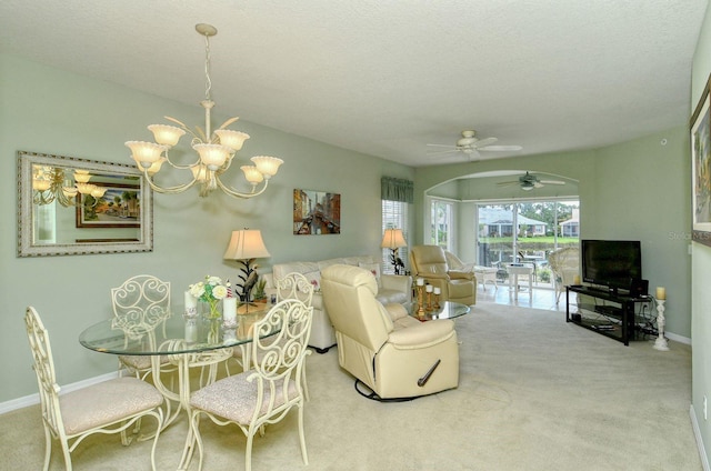 carpeted dining area with a textured ceiling and ceiling fan with notable chandelier