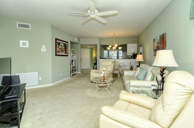 carpeted living room featuring a textured ceiling and ceiling fan with notable chandelier