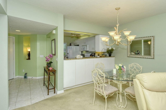 carpeted dining room featuring a textured ceiling and an inviting chandelier