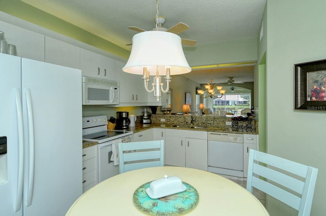 kitchen with white appliances, a textured ceiling, pendant lighting, a notable chandelier, and white cabinets