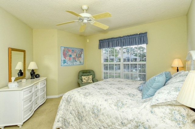 bedroom featuring ceiling fan, light carpet, and a textured ceiling