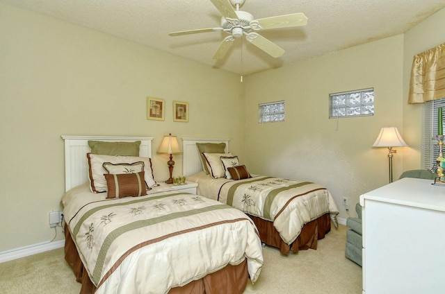 bedroom with ceiling fan, light colored carpet, and a textured ceiling