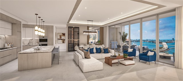 living room with a tray ceiling, a wealth of natural light, a chandelier, and a water view