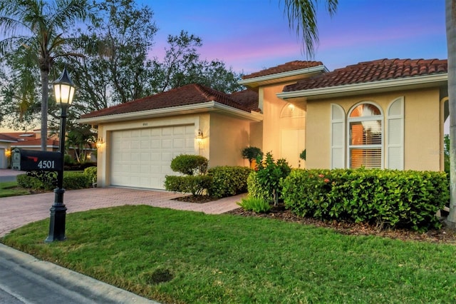 mediterranean / spanish-style home featuring a lawn and a garage