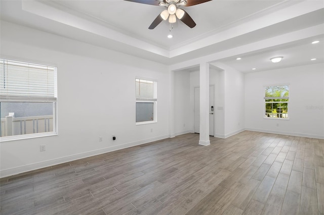 unfurnished room featuring a raised ceiling, ceiling fan, and light hardwood / wood-style floors