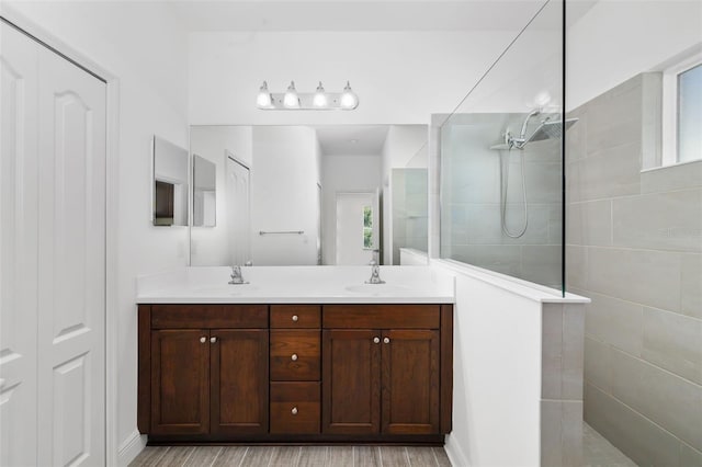 bathroom with hardwood / wood-style floors, vanity, and a tile shower