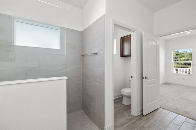 bathroom with tiled shower, hardwood / wood-style flooring, and toilet