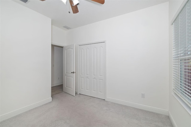 unfurnished bedroom with ceiling fan, light colored carpet, and a closet