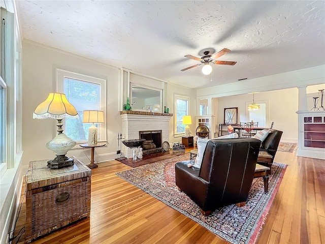 living room with a textured ceiling, plenty of natural light, wood-type flooring, and a fireplace