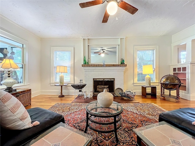 living room featuring a wealth of natural light, a fireplace, a textured ceiling, and light hardwood / wood-style flooring