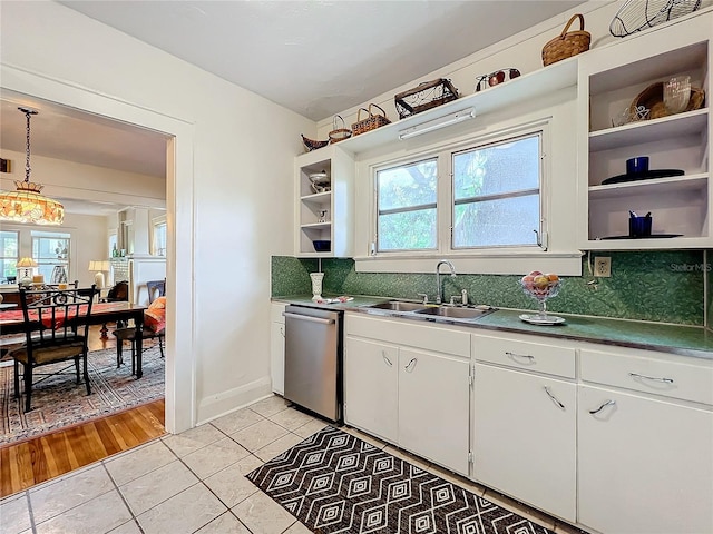 kitchen featuring white cabinets, sink, stainless steel dishwasher, decorative light fixtures, and light hardwood / wood-style floors