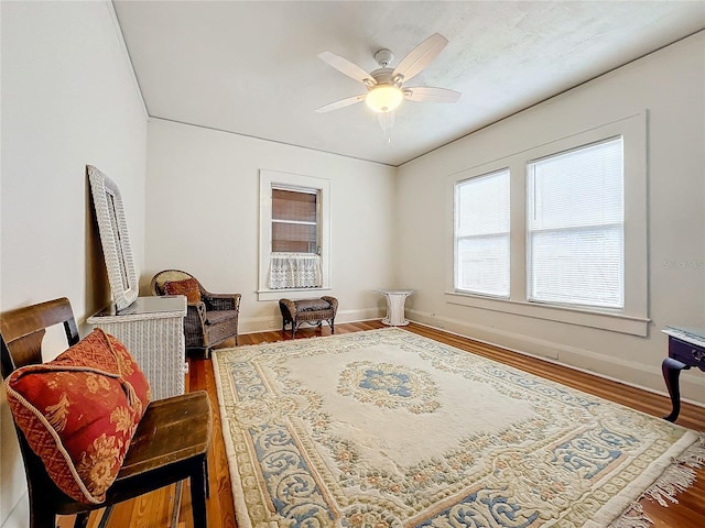 living area with wood-type flooring and ceiling fan