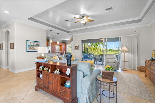 tiled living room with a raised ceiling, ceiling fan, and ornamental molding