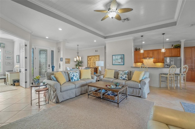 tiled living room with ceiling fan with notable chandelier and ornamental molding