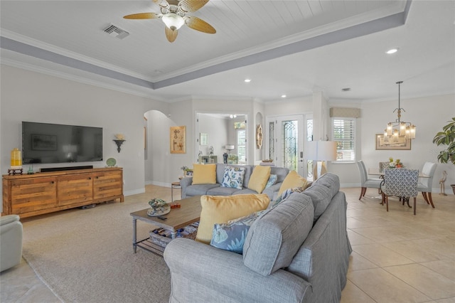 living room with light tile patterned flooring, ceiling fan with notable chandelier, and ornamental molding