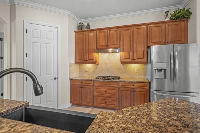 kitchen with ornamental molding, stainless steel appliances, dark stone counters, and sink