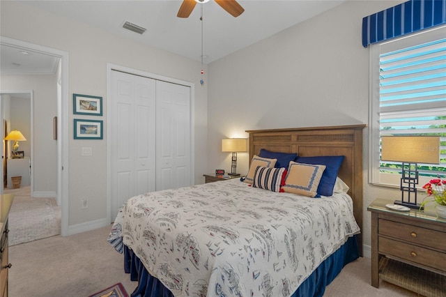 carpeted bedroom featuring ceiling fan, a closet, and crown molding