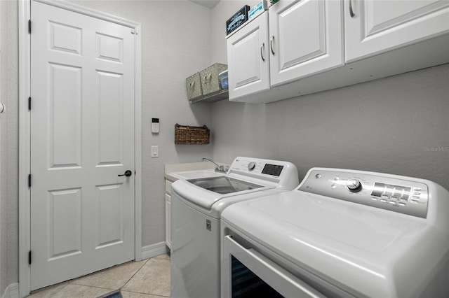 washroom with washing machine and clothes dryer, sink, light tile patterned floors, and cabinets