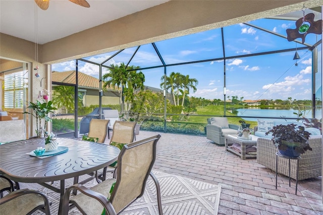 view of patio / terrace featuring a water view, ceiling fan, and a lanai