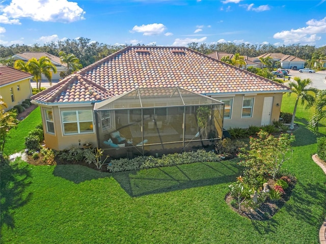 rear view of property featuring glass enclosure and a yard