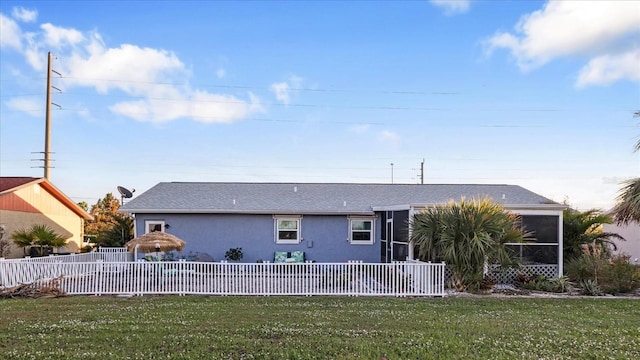 rear view of house with a sunroom and a yard