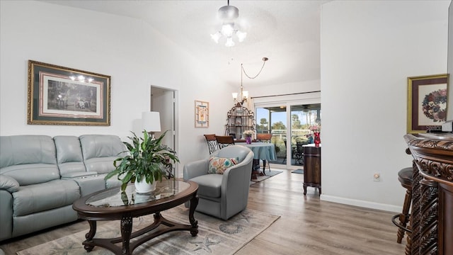 living room with a chandelier, light hardwood / wood-style flooring, and vaulted ceiling