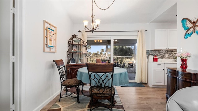 dining area with light wood-type flooring and an inviting chandelier