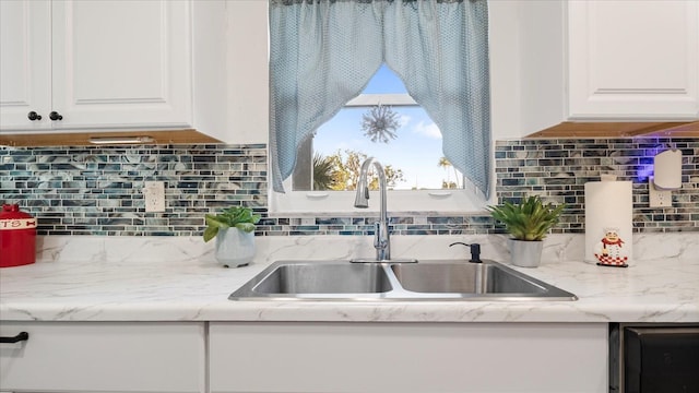 kitchen with tasteful backsplash, white cabinetry, and sink