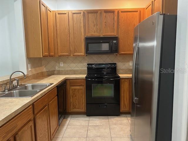 kitchen with decorative backsplash, sink, light tile patterned floors, and black appliances