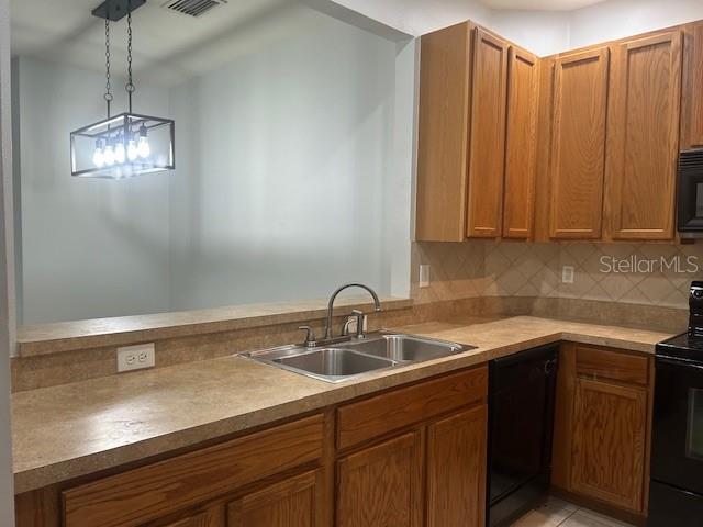 kitchen with decorative backsplash, sink, decorative light fixtures, and black appliances