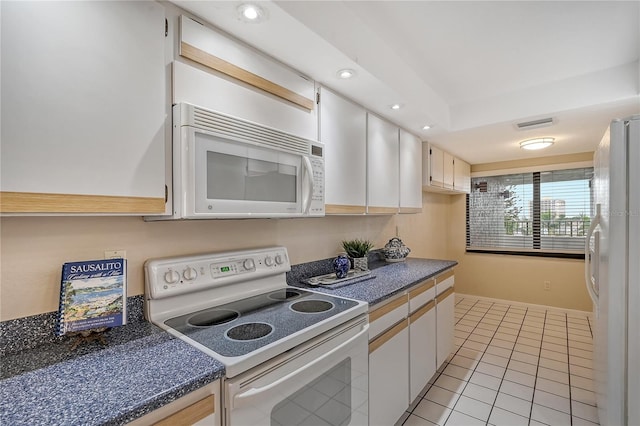 kitchen featuring white cabinets, light tile patterned flooring, and white appliances