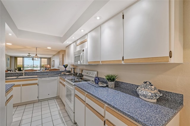 kitchen with kitchen peninsula, white cabinets, a chandelier, and white appliances