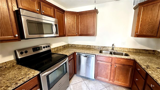 kitchen with light tile patterned floors, light stone countertops, sink, and appliances with stainless steel finishes