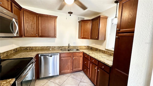 kitchen featuring light stone counters, stainless steel appliances, sink, light tile patterned floors, and hanging light fixtures