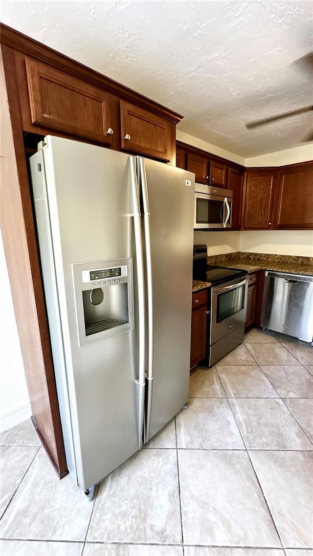 kitchen featuring light tile patterned floors, a textured ceiling, and appliances with stainless steel finishes