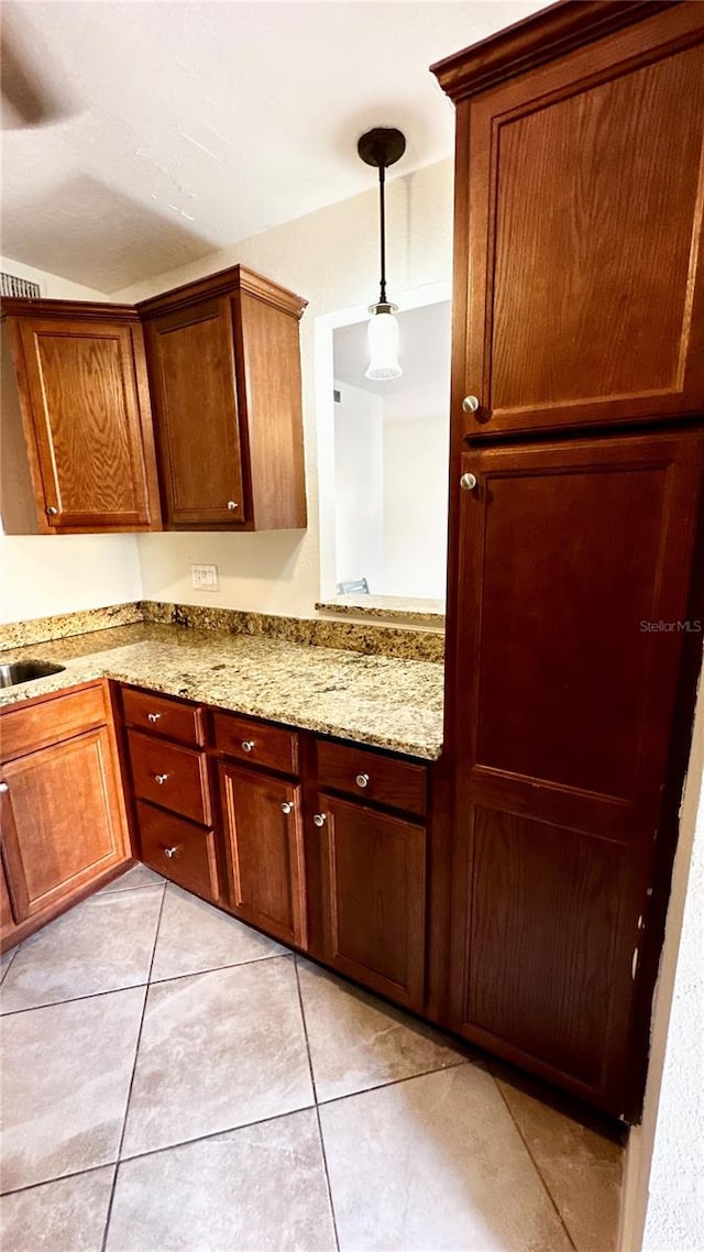 kitchen with light stone countertops, light tile patterned floors, and hanging light fixtures