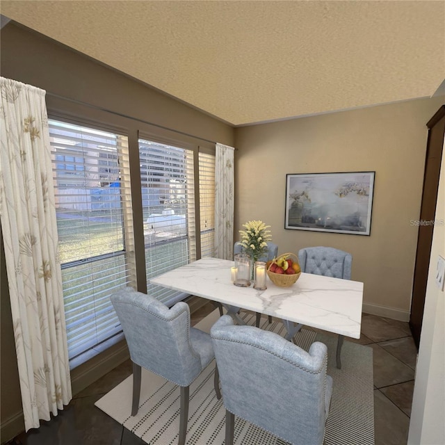 dining room with dark tile patterned floors and a textured ceiling