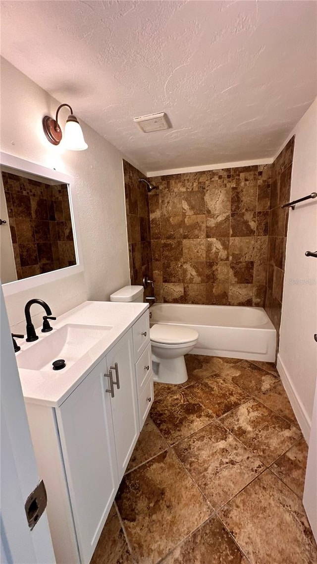 full bathroom with vanity, toilet, a textured ceiling, and tiled shower / bath