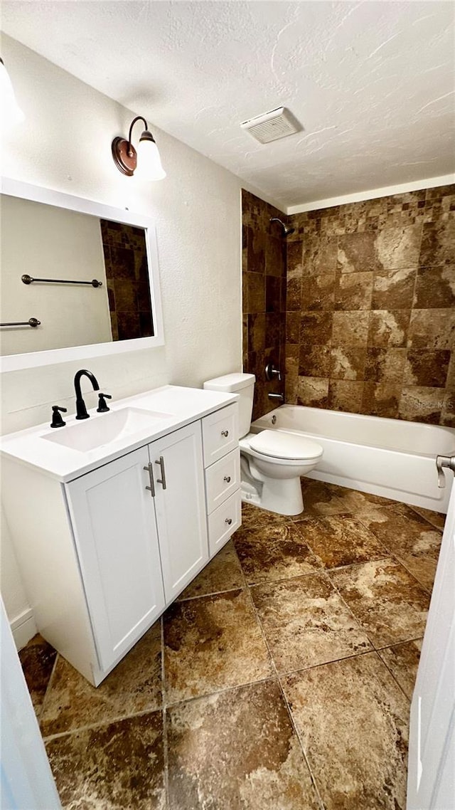 full bathroom featuring vanity, a textured ceiling, toilet, and tiled shower / bath