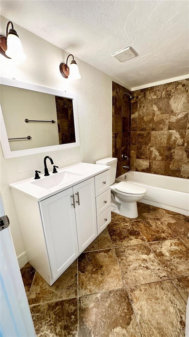 full bathroom featuring toilet, vanity, a textured ceiling, and tiled shower / bath combo