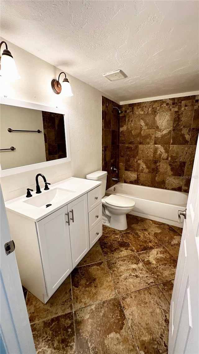 full bathroom with vanity, toilet, a textured ceiling, and tiled shower / bath combo