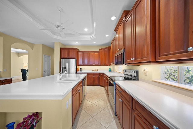 kitchen featuring sink, crown molding, appliances with stainless steel finishes, an island with sink, and a raised ceiling