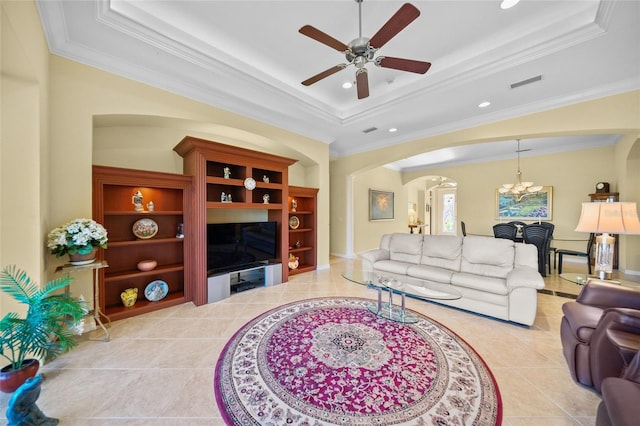 tiled living room featuring ceiling fan with notable chandelier, ornamental molding, a raised ceiling, and built in shelves