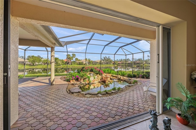 view of patio / terrace featuring a water view and glass enclosure